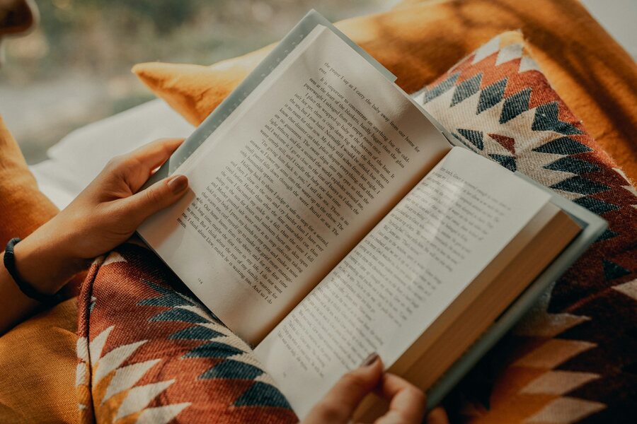 Hands holding an open book while reading.